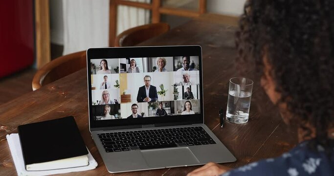 Diverse businesspeople engaged in group video call, laptop screen view over African businesswoman sit at desk take part in videoconference by business. Remote communication, videocall event concept