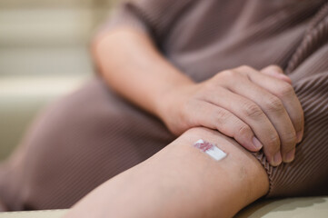 pregnant woman draws blood from an injection wound on a patient's arm.