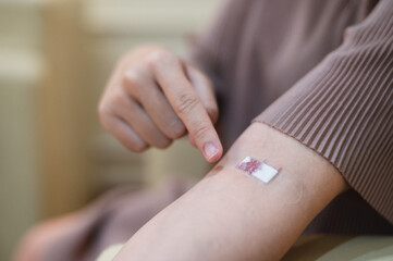 pregnant woman draws blood from an injection wound on a patient's arm.