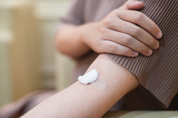 pregnant woman draws blood from an injection wound on a patient's arm.