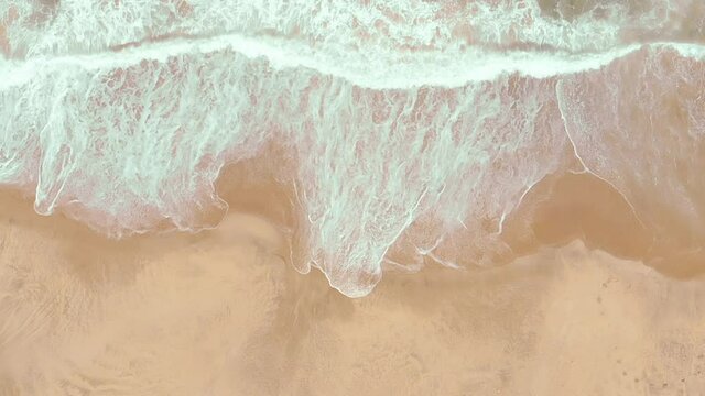 Static top shot aerial drone showing endless wild sea waves breaking on the sandy coast in slow motion