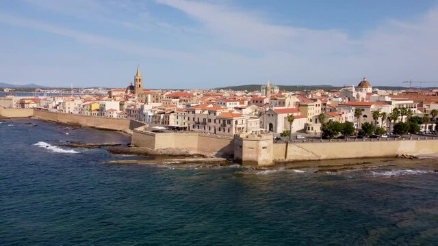 The scenic town of Alghero in Sardinia, Italy shot from a drone from outside the castle walls with a cathedral and the old town in the background