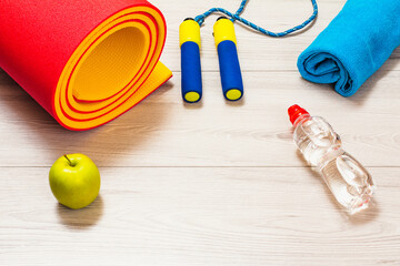 Yoga mat and different tools for fitness on floor in room.