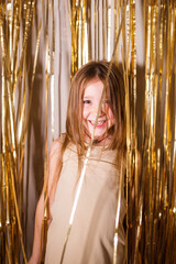 happy smile baby child girl on background of golden tinsel. concept of holiday, Christmas, party,...