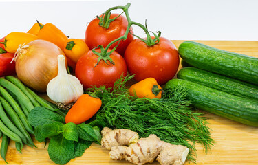 Fresh vegetables and greens on the board, food close up. Group of fresh vegetables on wooden table.
