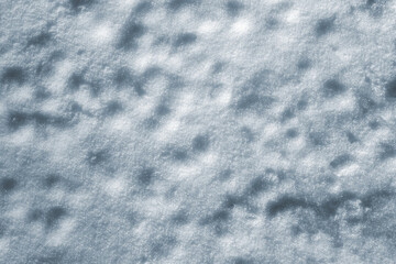 The natural texture of the uneven snow surface as a background for the design. Close-up view from above.
