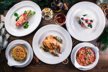 Delicious Christmas themed dinner table with roasted chicken, appetizers and desserts. Holiday concept.