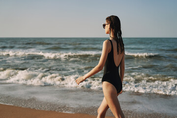 Fototapeta na wymiar cheerful woman in black swimsuit sunglasses beach walk travel