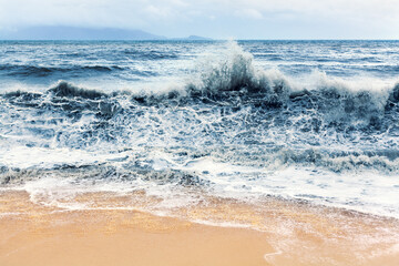 Sea storm, stormy ocean landscape, dark blue breaking waves motion, water splash, wave crest, white foam, dramatic seascape, rainy sky clouds, overcast, bad windy weather, tropical island beach nature