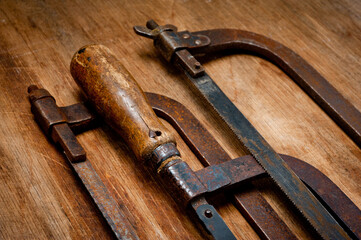 Old vintage metal hacksaws for metal shot on a wooden background.