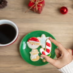 Merry Christmas with woman hand holding coffee cup and homemade cookie on table. Xmas eve, party, holiday and happy New Year concept