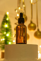 face essential oil with natural ingredients on podium on festive new year background with cristmas tre and baubles. New year or christmas gifts of skincare products and cosmetics.