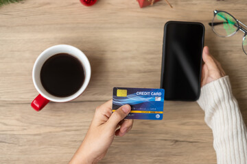 Hand holding credit card for online shopping on smartphone during drinking coffee. Merry Christmas eve, December, seasonal, Black Friday sale, New Year and holiday concept