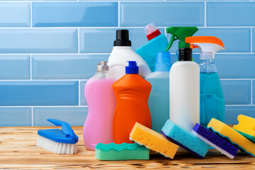 Household detergents and cleaning tools against blue tile background