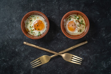 Two fried eggs in a round ceramic dish in the form of eyes. Cooked small fried eggs is a simple breakfast