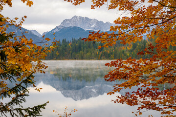 Herbstlaub umrahmt See und Berge in den Alpen