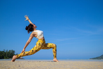 Exalted Crescent Lunge. Asian woman doing yoga poses on a beach in Koh Pha Ngan island, Thailand