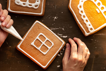 Decoration gingerbread house by frosting on wooden background