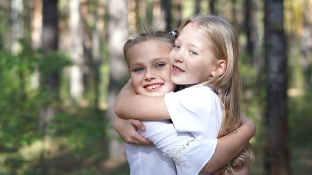 Young pretty girls hugging outdoors. Children.