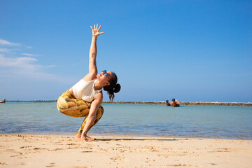 Revolved Chair with Arms Extended. Asian woman doing yoga poses on a beach in Koh Pha Ngan island, Thailand