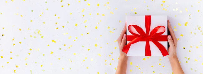 banner gift box in female hands on a white background with gold glitter	
