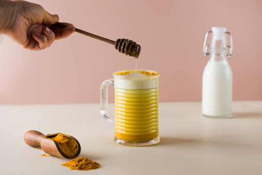  A drop of honey drips into a latte turmeric mug. Moon milk for better sleep. 