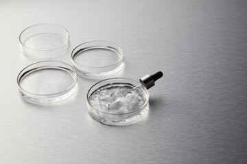 Petri dish and dropper with water ripple on silver background