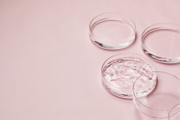 Petri dishes with water and ripple in light pink background for skincare