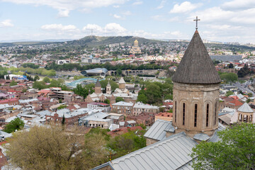 Obraz premium A panoramic view of Tbilisi, Georgia, featuring the city's skyline with a mix of modern and historical architecture, under a cloudy sky.