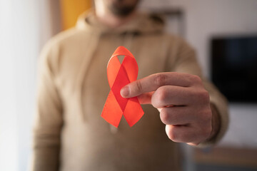 Caucasian man holding red hiv aids ribbon.