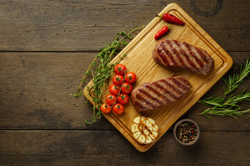 Ketogenic delicious two top blade beefsteaks with herbs and spices on wooden background