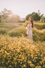 Fototapeta premium Young attractive woman having fun in yellow flower field