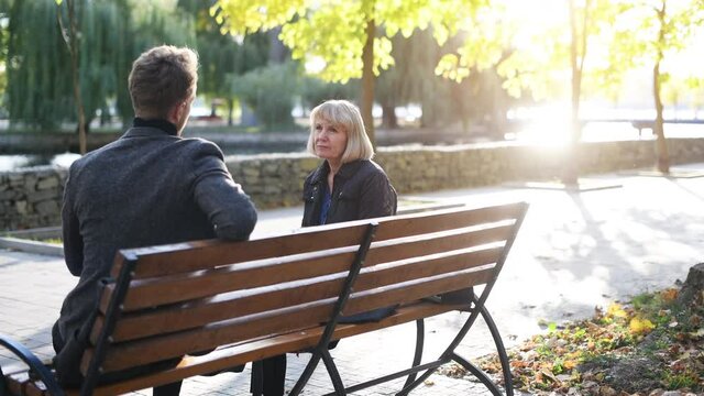 Grandmother with young guy in formal clothes have conversation in an autumn park