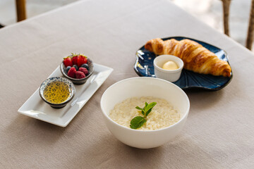 Served breakfast with porridge and croissant on restaurant table