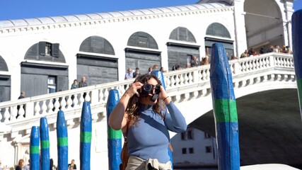 Europe, Italy, Venice - young girl taking pictures in Venezia in Canal Grande Rialto Bridge   -...