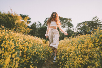 Young attractive woman having fun in yellow flower field