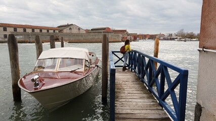 Fototapeta premium Europe, Italy , Venice - girl admires the beauty of murano and Venice, the city of love, walking along the river - goes up on the wooden bridge to see the lagoon with boats and gondolas