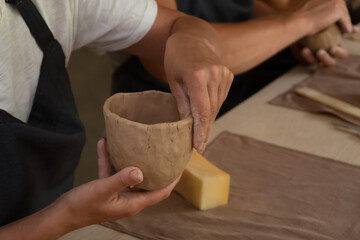 Close up shot of hands of crafts people, working with clay in pottery studio