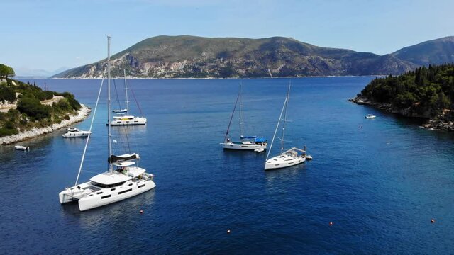 Catamaran And Sailboats In The Ionian Sea At The Foki Beach In The Island Of Kefalonia In Greece. aerial sideways
