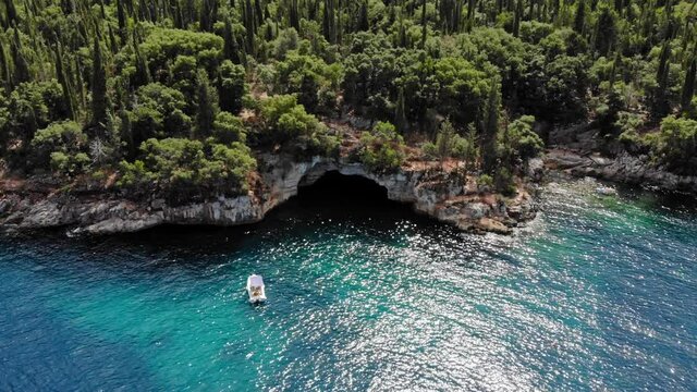 Small Boat Docked Near The Forest-Covered Seashore In Foki Beach In Kefalonia, Greece. aerial