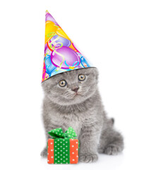 Funny kitten wearing party cap sits with gift box. isolated on white background