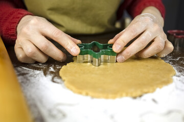 Cutting snowflake cookies from dough with an iron mold. Woman cats cookies for children at christmas time. The concept of a family holiday.