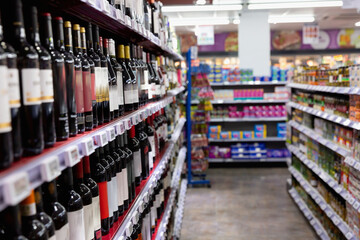Shelves with wine at beverage section of supermarket. Different bottles of wine on food store shelves