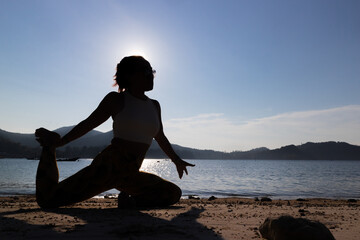 Mermaid pose. Asian woman doing yoga poses on a beach in Koh Pha Ngan island, Thailand