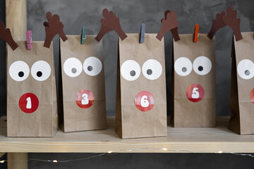 Close-up advent calendar in craft packages with numbers of days, Christmas advent presents on the shelf, gray background.