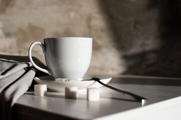 Closeup white cup on light gray wall background on a nice summer morning