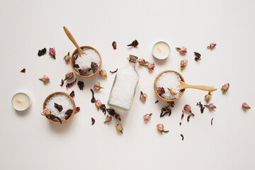 Wooden bowls and bottle filled with white bath sea salt with dry rose buds and candles. Beauty...