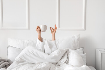 Morning of young woman drinking tea in bed - obrazy, fototapety, plakaty