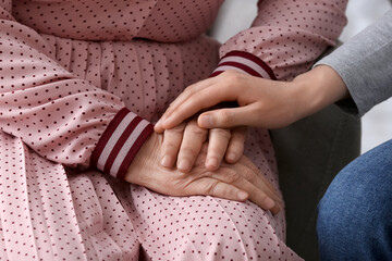 Young woman holding hands of grandmother at home