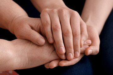 Fototapeta premium Young woman holding hands of grandmother, closeup